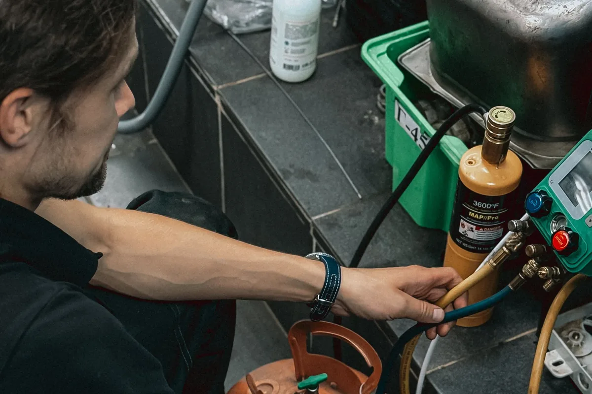 Technician checking a refrigerator cooling system with gauges