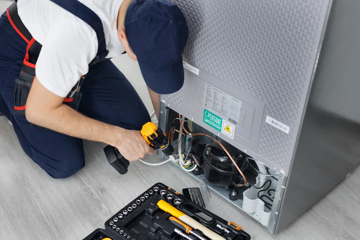 Technician working on the back panel of a refrigerator