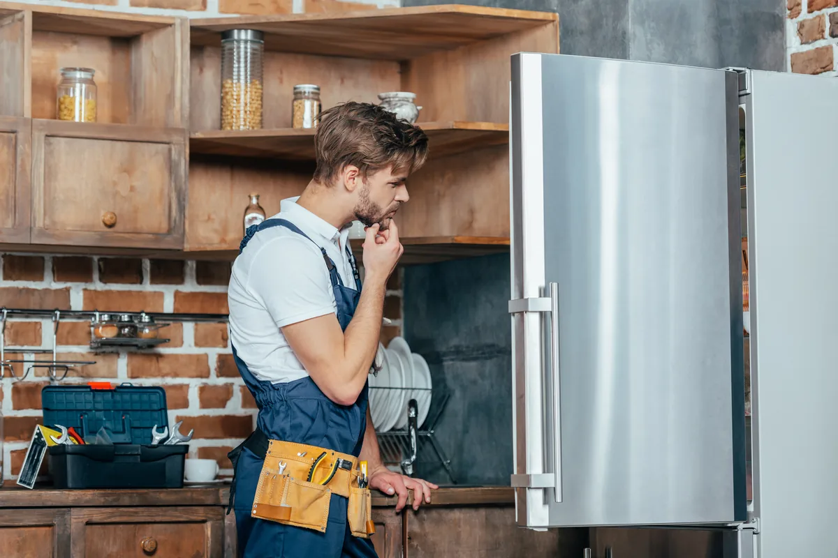 Refrigerator technician inspecting a fridge in a home kitchen