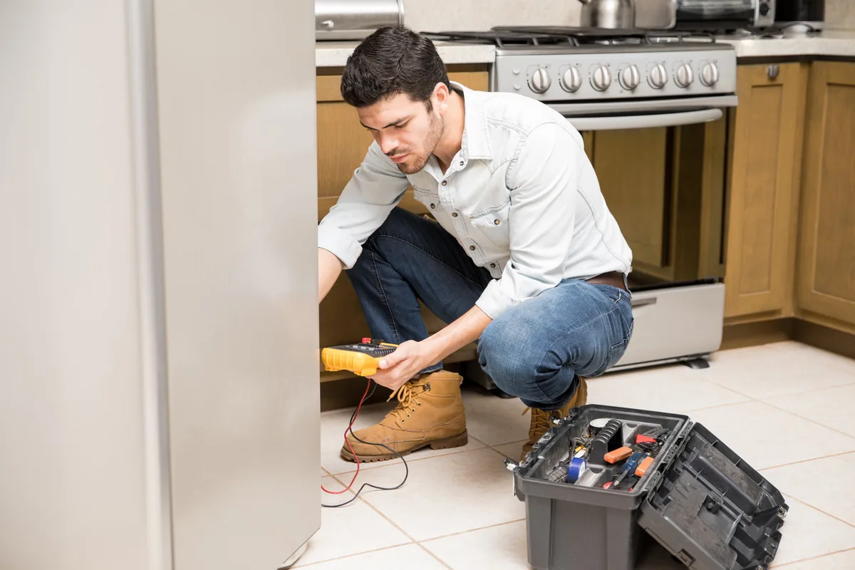 Technician testing a refrigerator with a multimeter